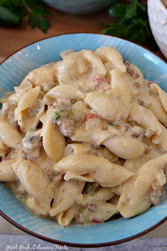 An overhead shot of a blue bowl filled with creamy Italian Sausage Pasta showing the pasta shells, creamy sauce and Italian sausage.