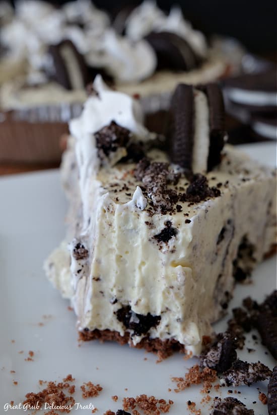 A slice of no bake Oreo pie on a white plate with a bite removed from the front piece of the pie..