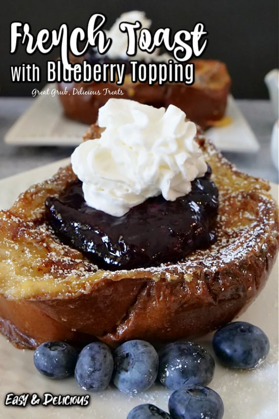 A close up shot of a piece of French toast with blueberry topping and whipped cream.