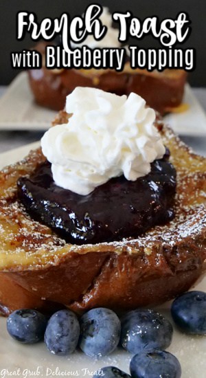 A close up photo of a piece of French toast with blueberry topping on a white plate with fresh blueberries on the plate.