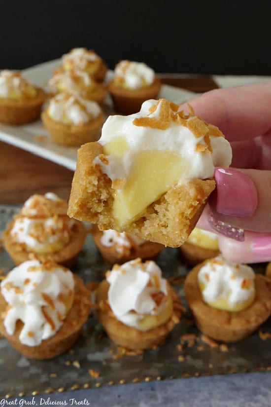 A close up photo of a tray of coconut cream cookie bites, with a close up photo of a bite taken out showing the coconut filling.