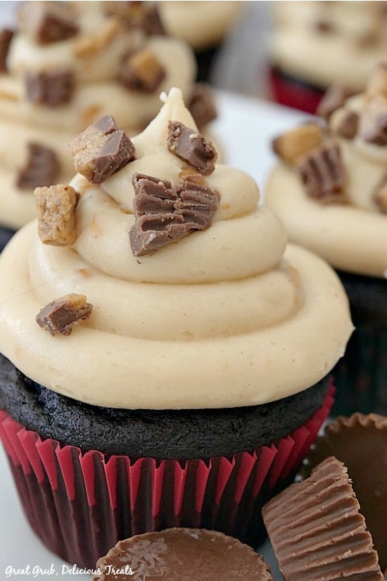 A close up of a chocolate cupcake with peanut butter frosting topped with chopped peanut butter cups.