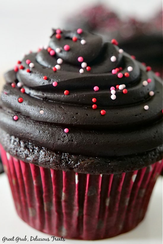 A Dark Chocolate Zucchini Cupcake frosted with a delicious dark chocolate frosting with red, white and pink sprinkles.