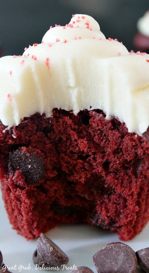 A super close up photo of a red velvet cupcake with cream cheese frosting that has a bite taken out of it.