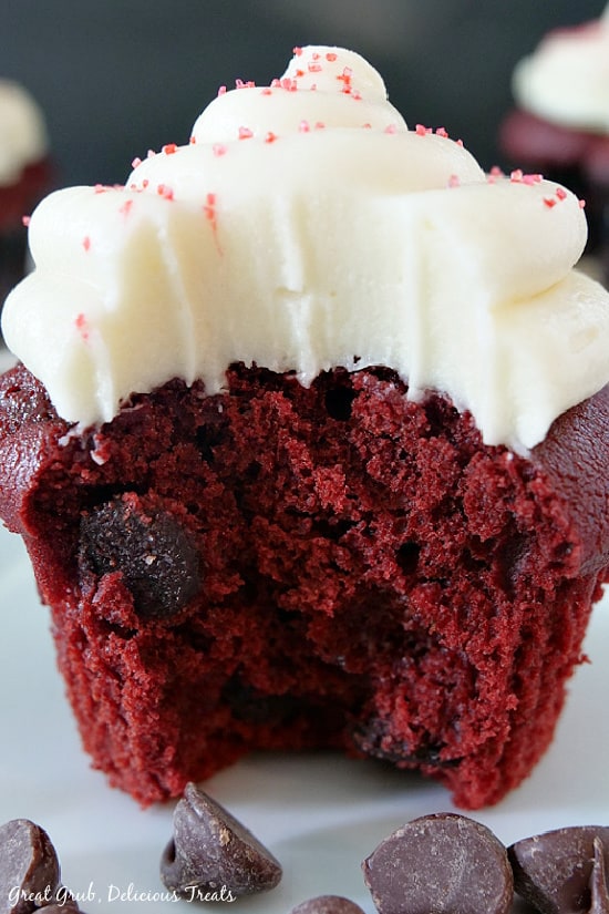 A close up picture of a red velvet cupcake with a bite taken out of it showing the teeth marks in the cream cheese frosting.