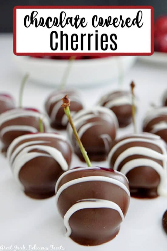 Chocolate covered cherries lined up on a white plate.