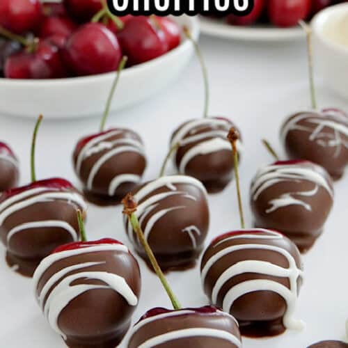 Chocolate covered cherries lined up on a white plate.