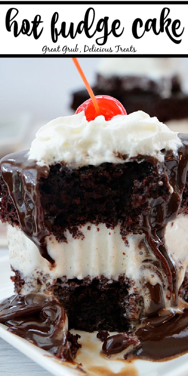 A close up photo of hot fudge cake with a bite taken out of it, hot fudge on top, and topped with whipped cream and a cherry.