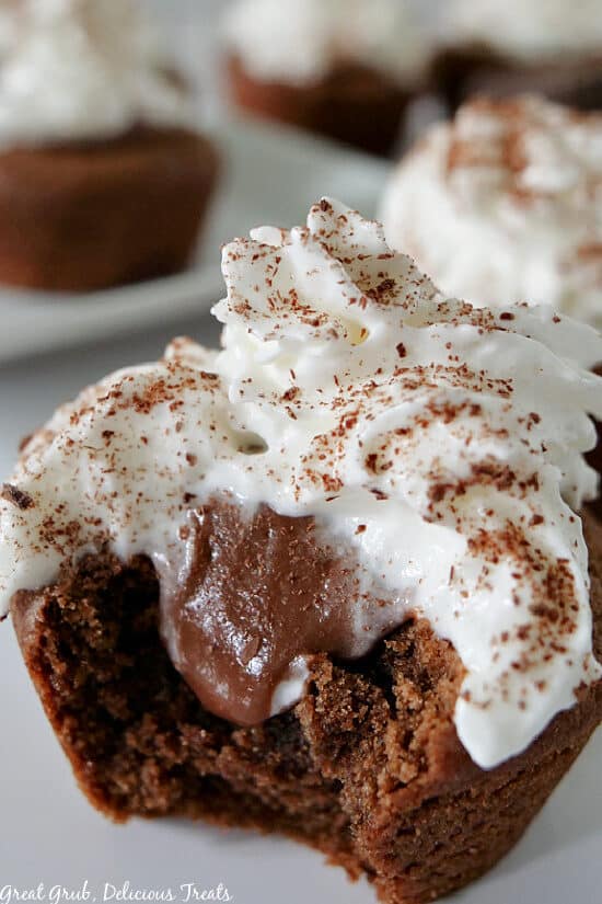 A super close up photo of a single Chocolate Cream Pie Cookie Bite with a bite taken out of it showing the chocolate pudding inside, topped with whipped cream.