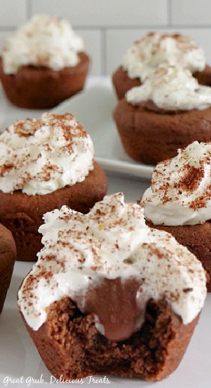 A close up shot of a chocolate cream pie cookie bite with a bite taken out of it with more cookie bites in the background.