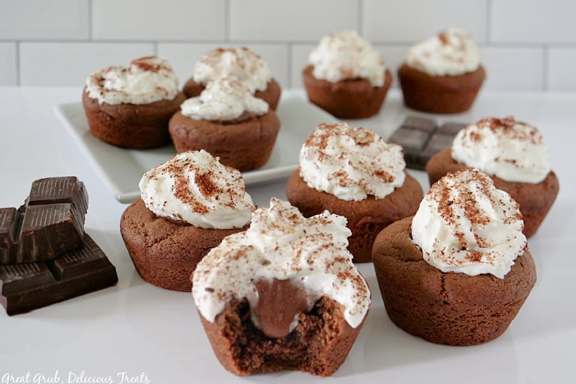 A horizontal photo of Chocolate Cream Pie Cookie Bites on a white surface with a few pieces of chocolate on the left hand side.