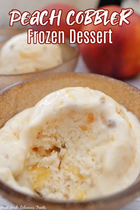 A close up photo of a scoop of peach cobbler frozen dessert in a gold bowl, with a bite taken out and peaches in the background.