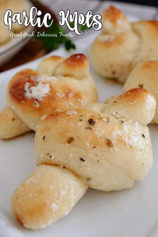 A white plate with 4 garlic knots on it and the title of the recipe at the top left corner of the photo.