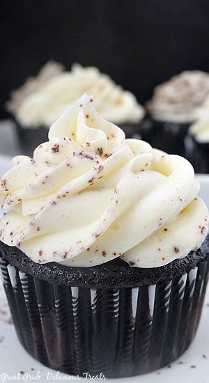 A close up photo of a chocolate cupcake with white frosting and crushed up oreos.
