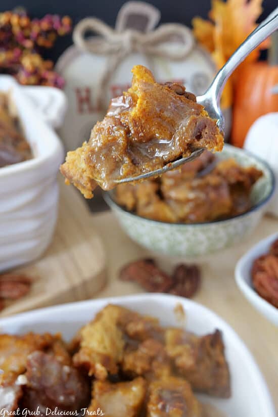 A spoonful of Pumpkin Pecan Bread Pudding held up close to the camera lens.