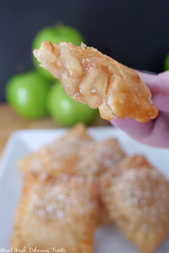A super close up photo of a apple pie ravioli being held up to show the apple filling.