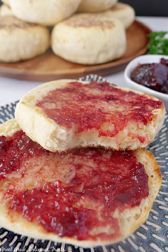 An English muffin cut in half with raspberry jelly spread on both pieces.