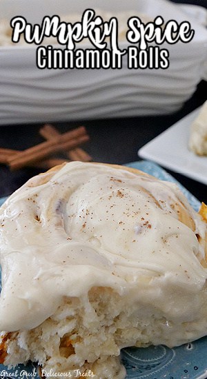 A blue plate with a pumpkin spice cinnamon roll on it with the title of the recipe at the top center.