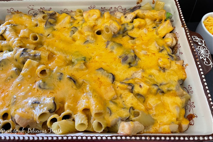 A decorative baking dish filled with cheesy chicken broccoli casserole with melted cheese all over the top.