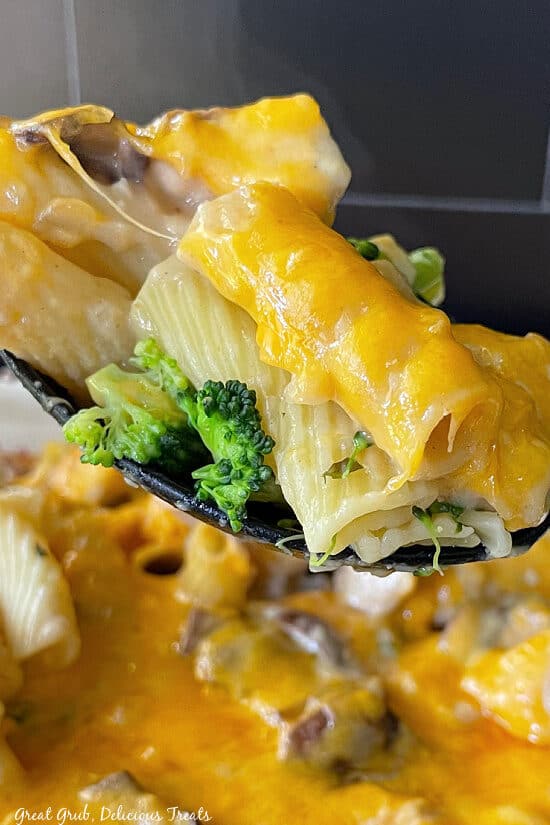 A super close up photo of a spoonful of chicken broccoli pasta casserole on it.
