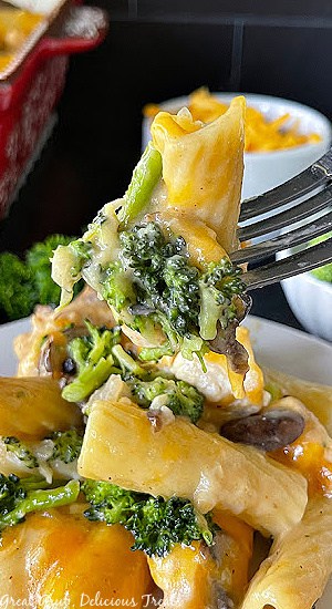 A white plate with chicken and broccoli casserole on it with a bite sitting on a fork.