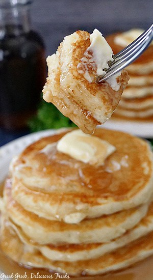 A bite of buttermilk pancakes on a fork showing the butter and syrup on the pancakes.