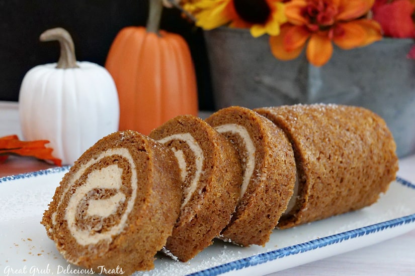 A horizontal photo of a pumpkin cake roll with three slices cut and laying up against the remaining cake roll.