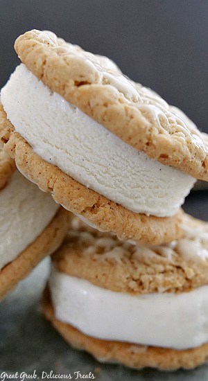 Three ice cream sandwiches with vanilla ice cream stacked up on a white plate.