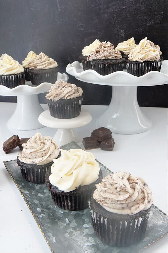 A sliver tray with 3 cupcakes on it with 3 different size cake stands with cupcakes on them too.