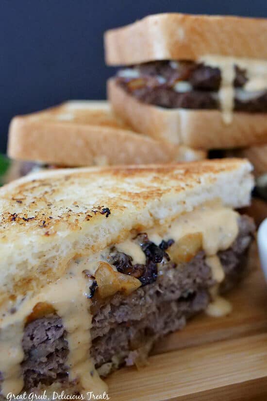 A close up photo of half a patty melt with more patty melts stacked up in the background.