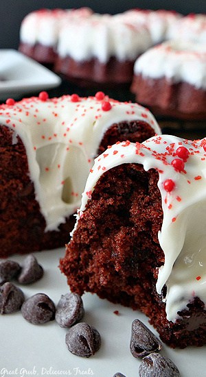 A mini red velvet Bundt cake on a white plate that has been cut in half.
