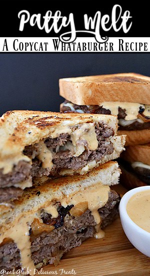 A couple patty melts on a wood board with a small white bowl of creamy sauce in it.