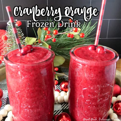 Two glasses filled with frozen cranberry orange freeze garnished with black and red plaid straws both sitting on a black and white checkered round tray.