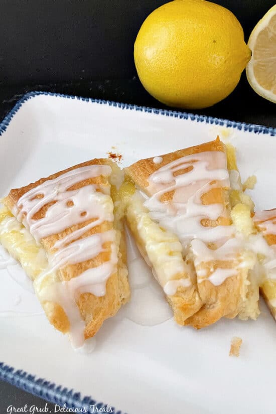 A white plate with blue trim with a few slices of lemon pastries on it.