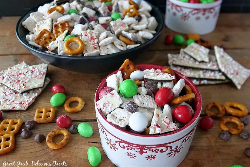 Two bowls filled with puppy chow and the ingredients also placed around the bowls on a wood surface.