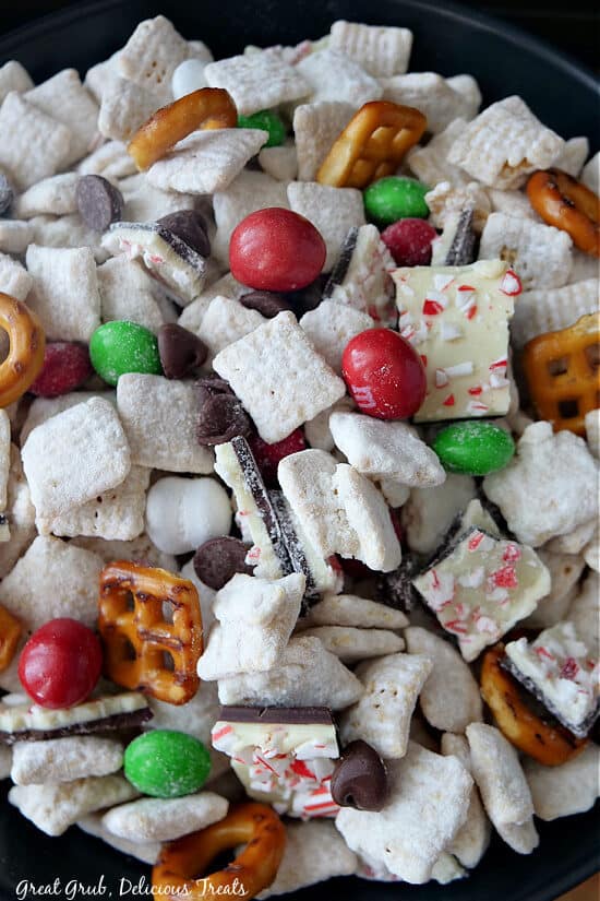 A close up photo of all the ingredients in this puppy chow recipe, Chex cereal, mint chocolate candies, pretzels and peppermint bark.