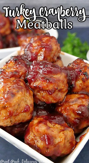 A white square bowl filled with meatballs made with turkey and covered in a cranberry barbecue sauce.