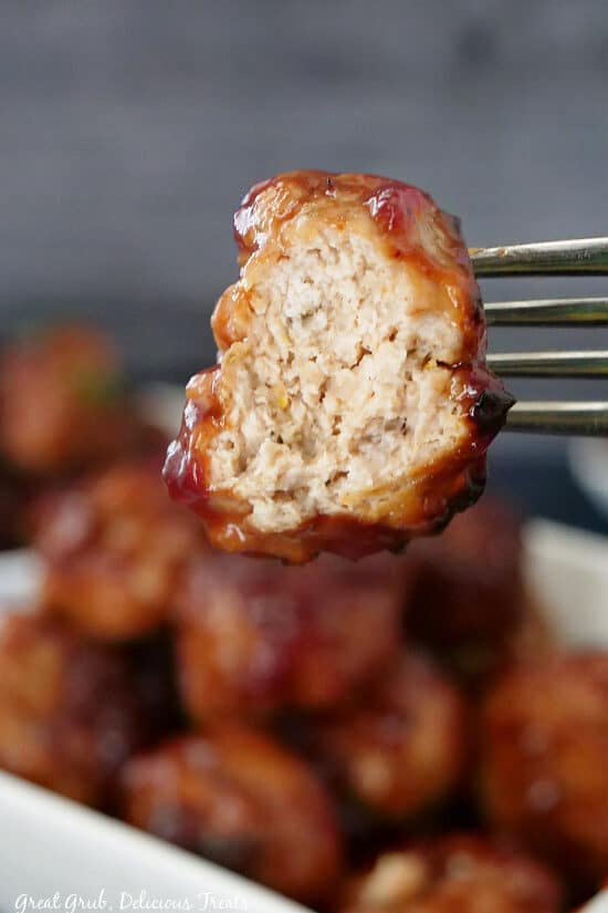 A super close up of a meatball on a fork with a bite taken out of it.