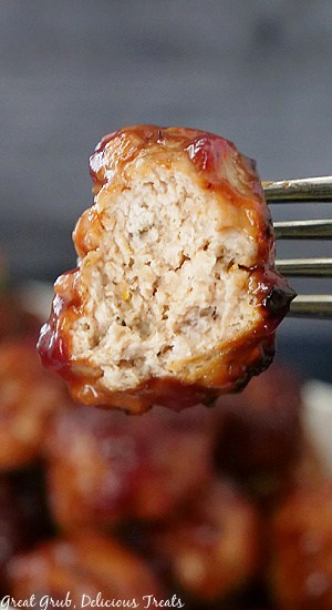A super close up of a meatball on a fork with a bite taken out of it.