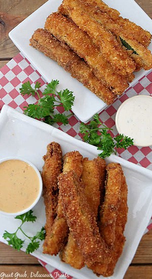 An overhead photo of fried zucchini strips on white plates with dipping sauce.