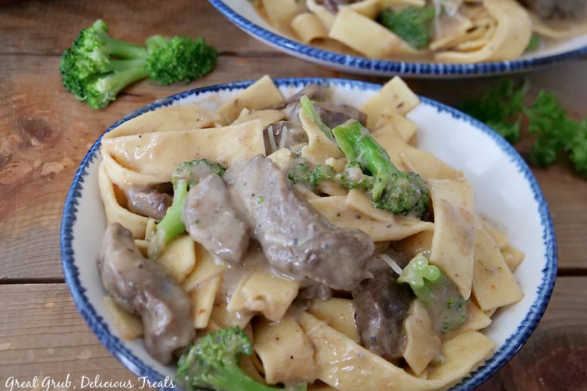 A white bowl filled with beef and broccoli with pasta tossed in a creamy sauce.