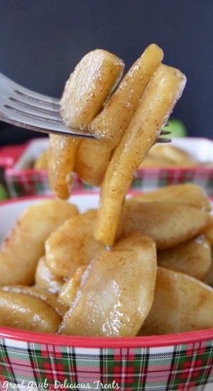 A close up of a fork with fried apples on it.