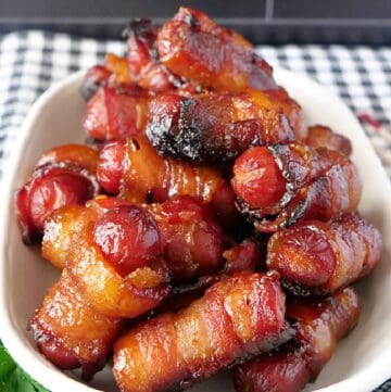 A white bowl filled with bacon wrapped little smokies.
