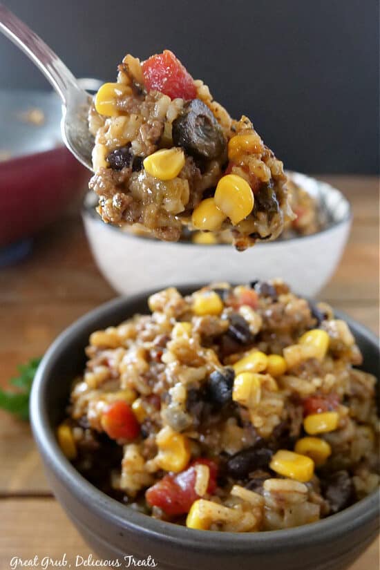 A close up of a spoonful of ground beef and rice showing all the ingredients from corn, olives, diced tomatoes, onions, meat and rice.