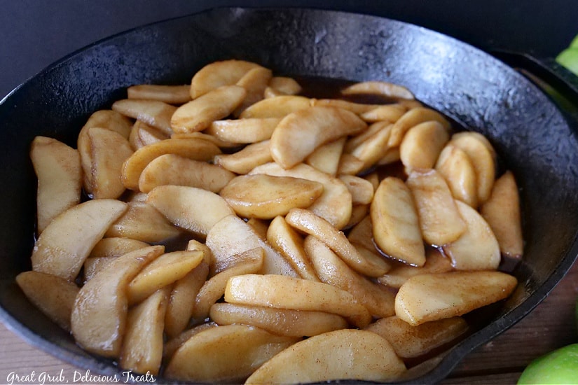 Fried apples laid out in a large cast iron skillet.