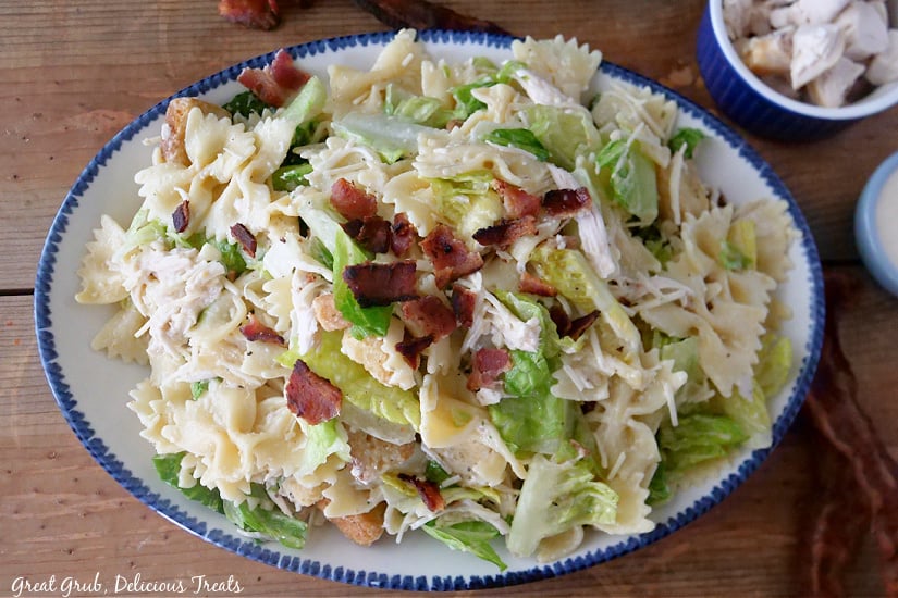 A white bowl with blue trim filled with a chicken bacon Caesar pasta salad.