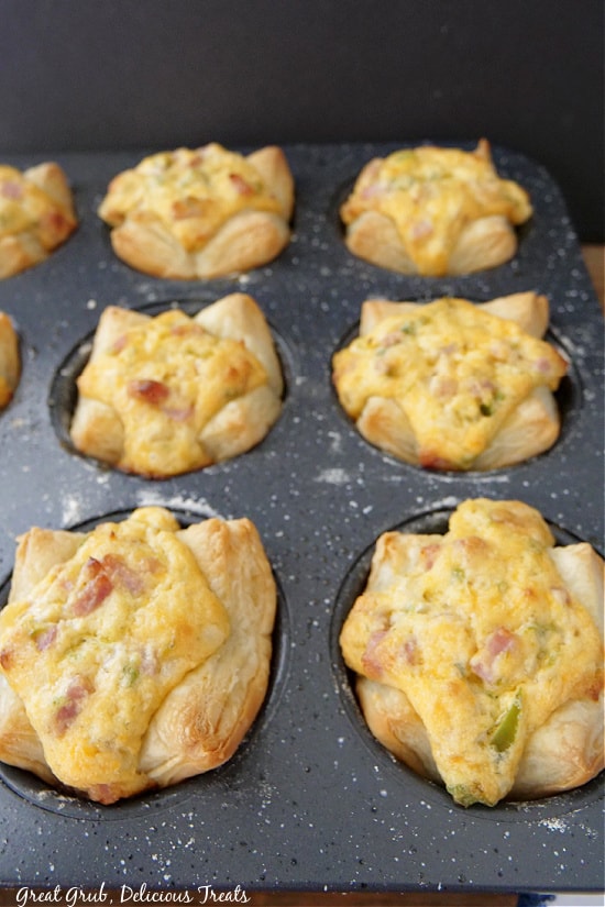 A muffin pan with freshly baked puff pastries in it.