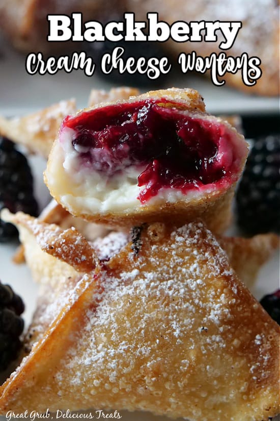 Blackberry wontons stacked up with a bite taken out of it, showing the inside and sprinkled with powdered sugar.
