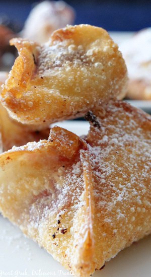 Fried wontons on top of each other, sprinkled with powdered sugar.