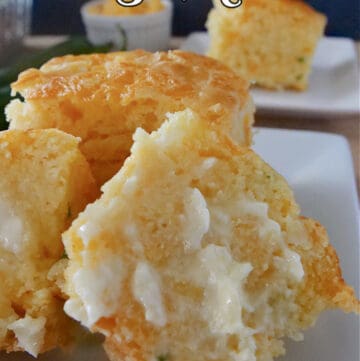 A white plate with a piece of cornbread cut in half and lathered with butter.